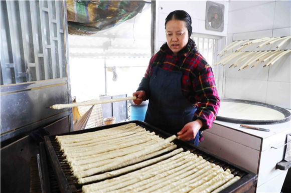 1月27日，梁平區(qū)禮讓鎮(zhèn)同河村8組，村民在把裹好的豆筋放到木箱上。劉輝 攝