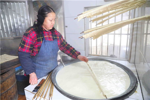 1月27日，梁平區(qū)禮讓鎮(zhèn)同河村8組，村民用竹棍在鐵鍋內(nèi)裹豆筋。劉輝 攝